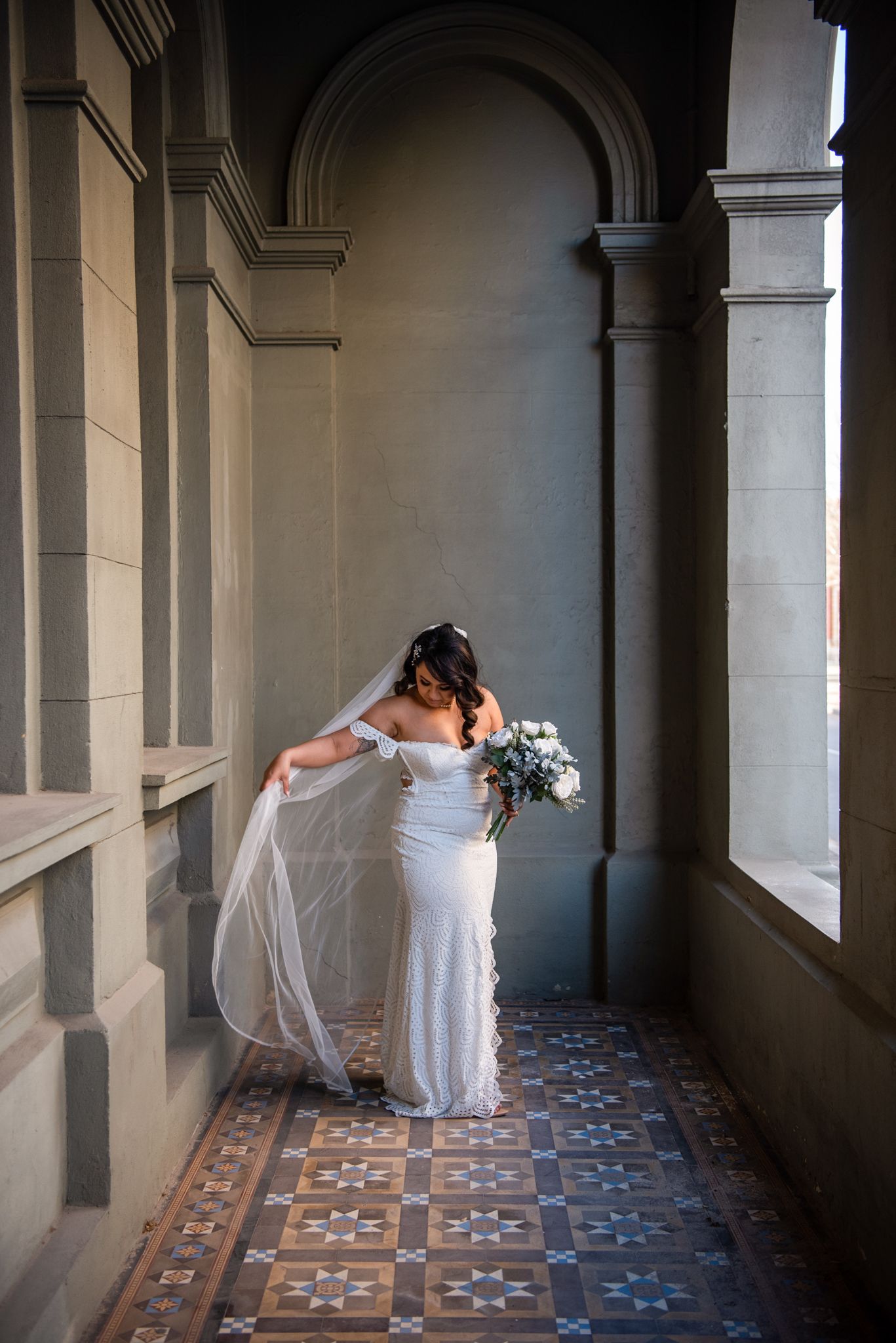 A bride in a white gown and veil moving gracefully through an ornate columned verandah in Fremantle, Perth, Australia