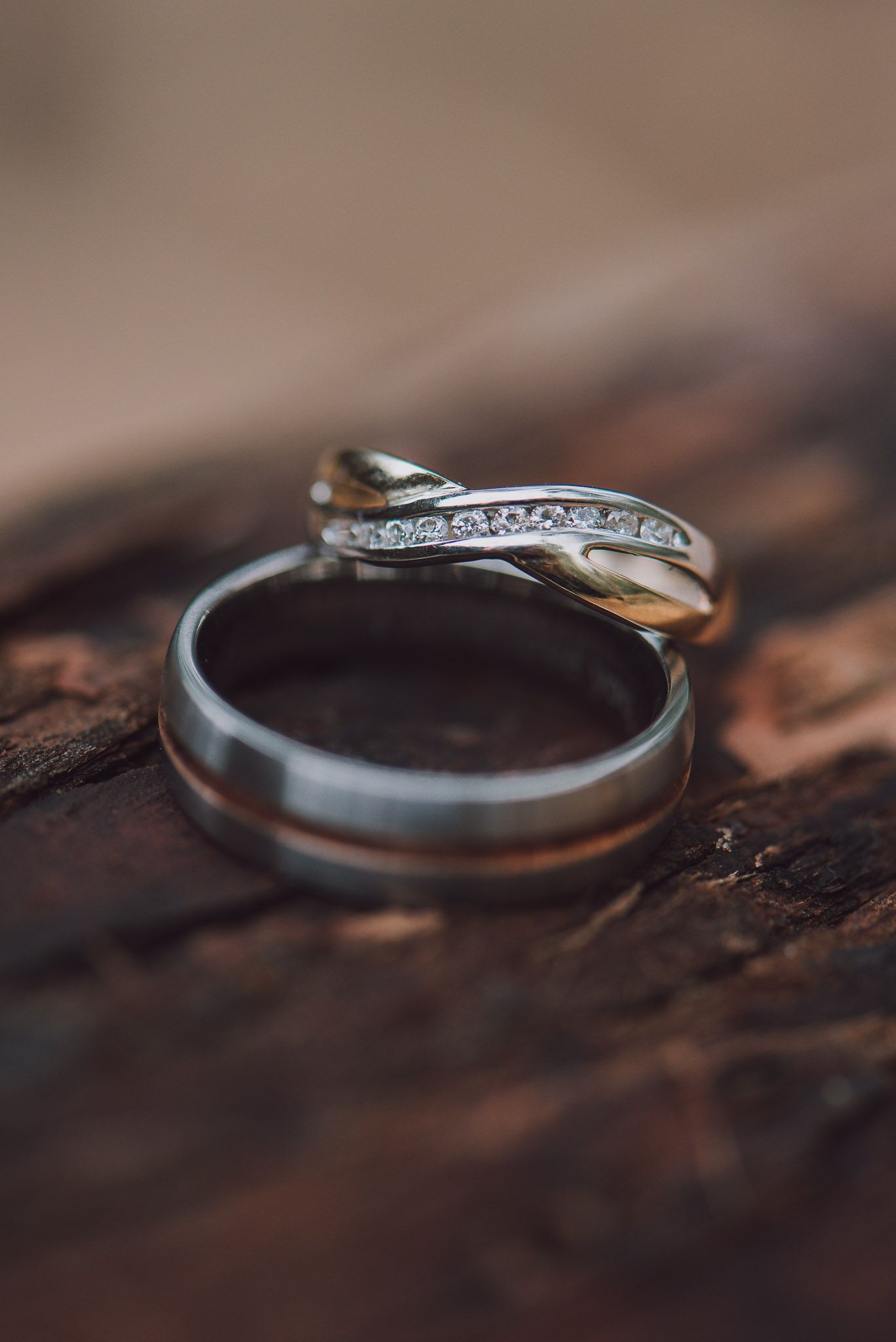 Wedding rings with diamonds on a textured wooden surface captured in intimate macro detail.