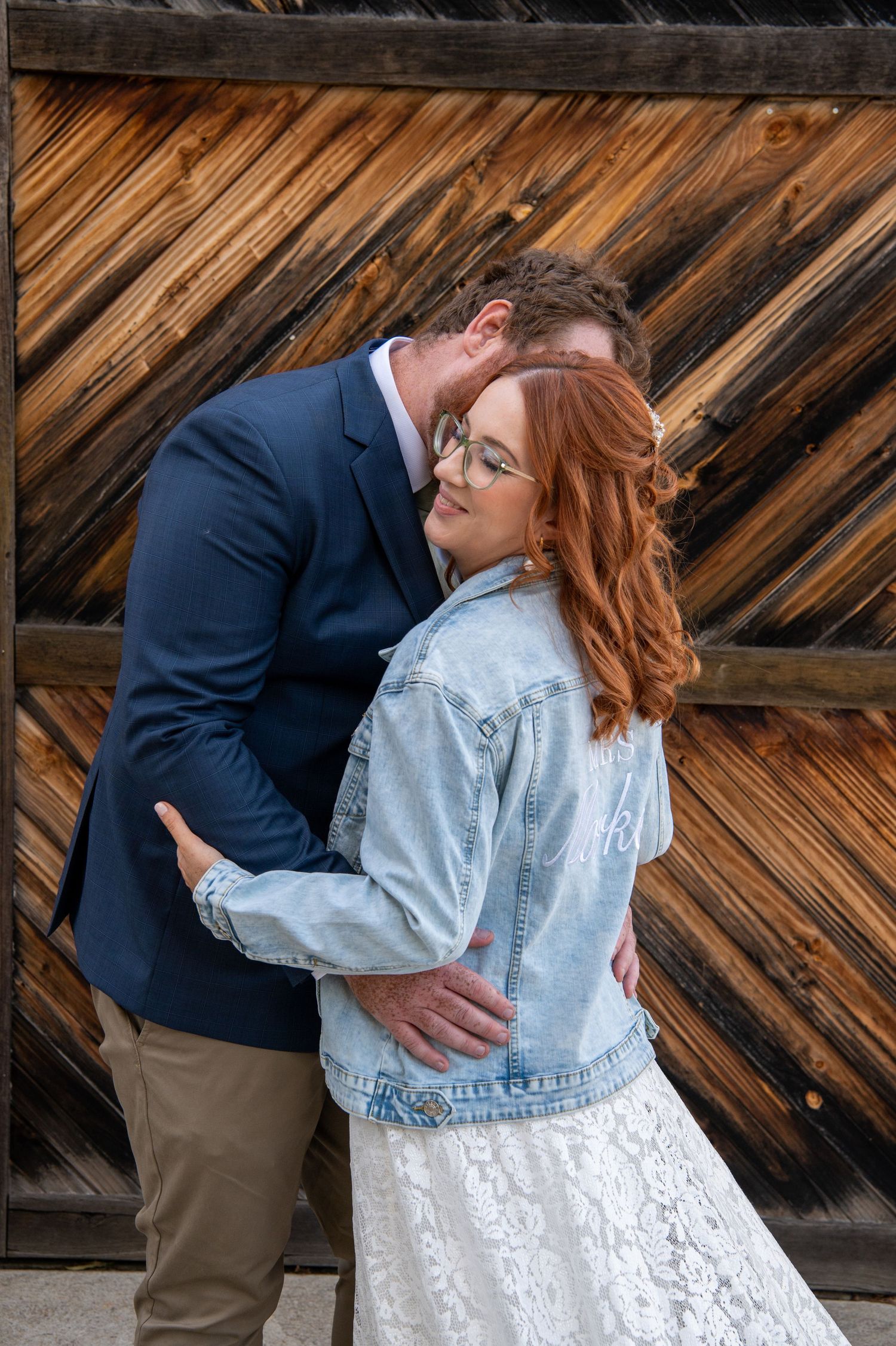 A romantic moment between newlyweds against a wooden wall backdrop.