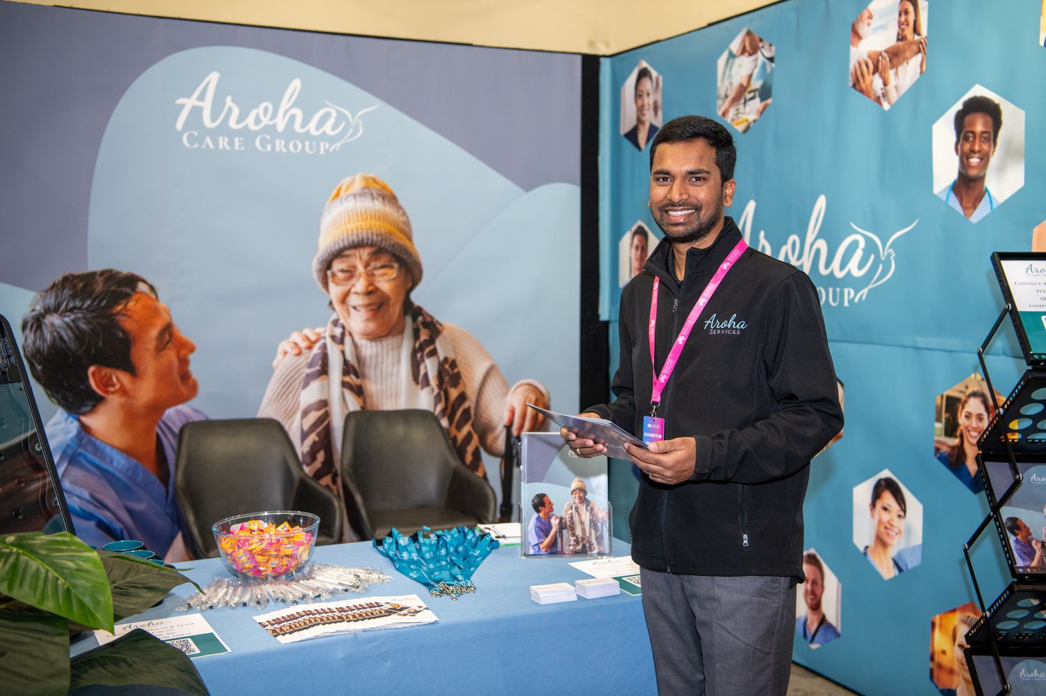 Four people serve customers at a counter with a bright blue wall displaying the Aloha text in the background.