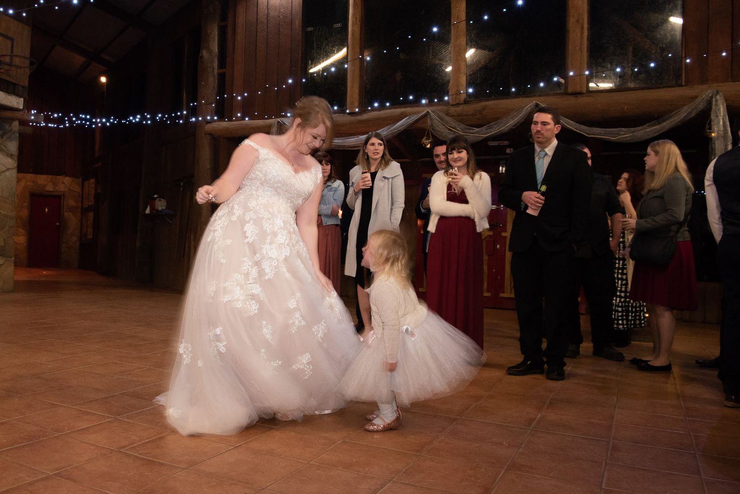 Wedding reception panorama featuring couples dancing under twinkling lights in a dimly lit venue.