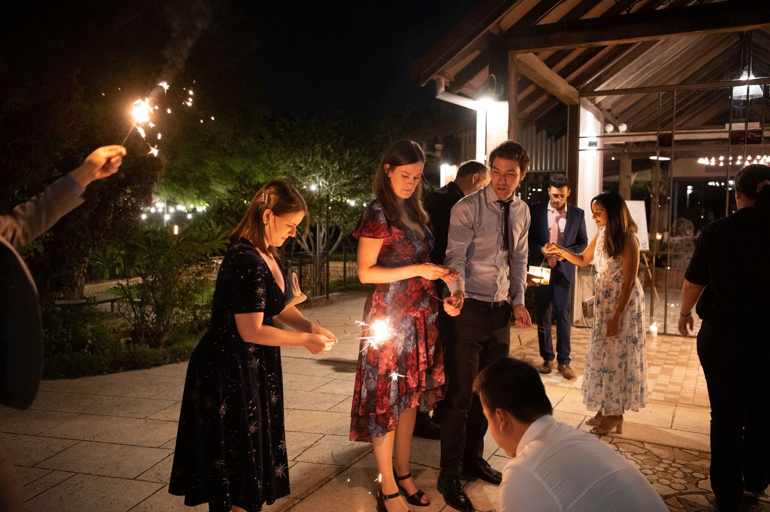 Wedding guests holding sparklers during an evening celebration outdoors.