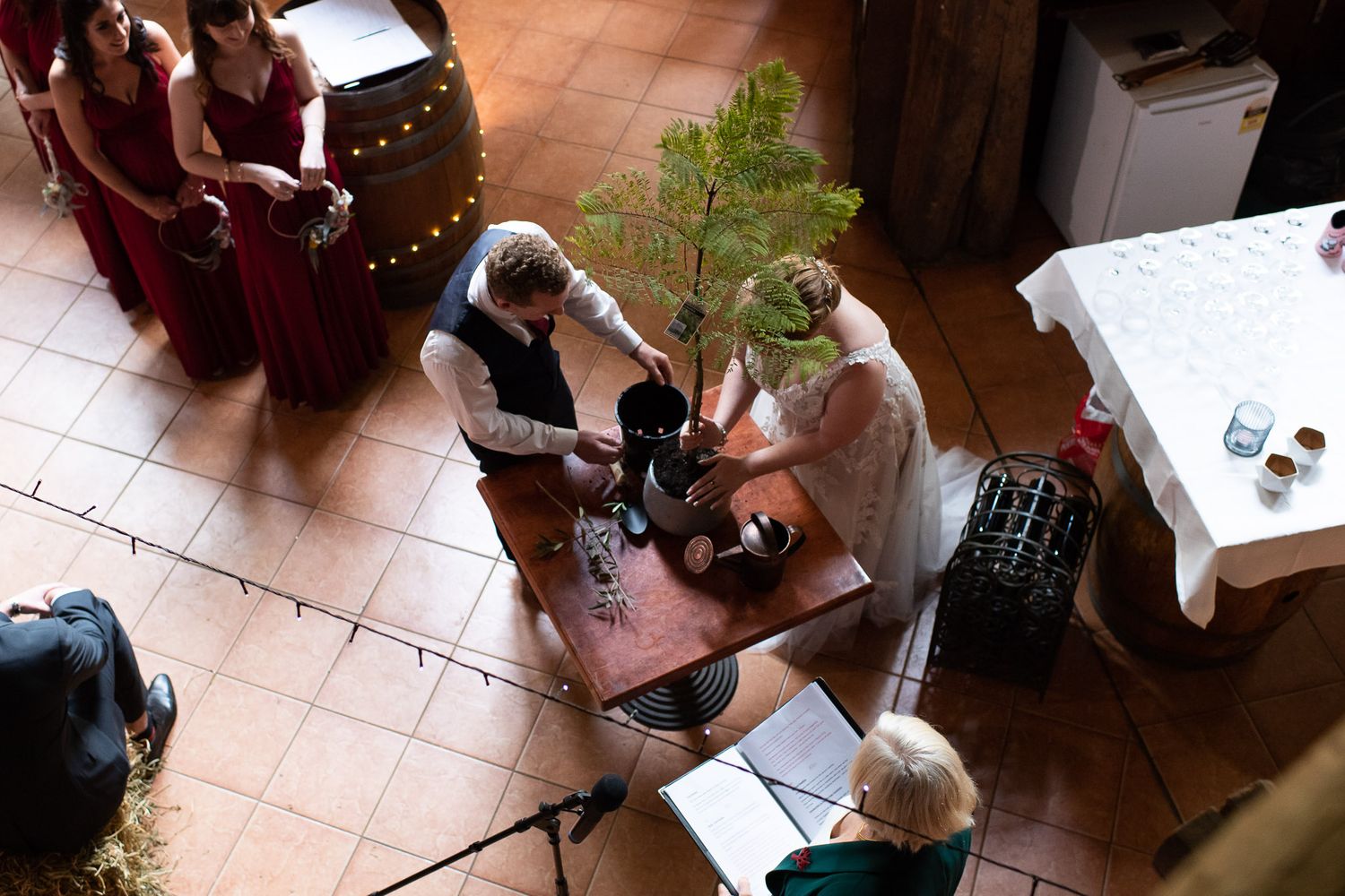 Overhead view of wedding party gathered around small table during an indoor reception ceremony.