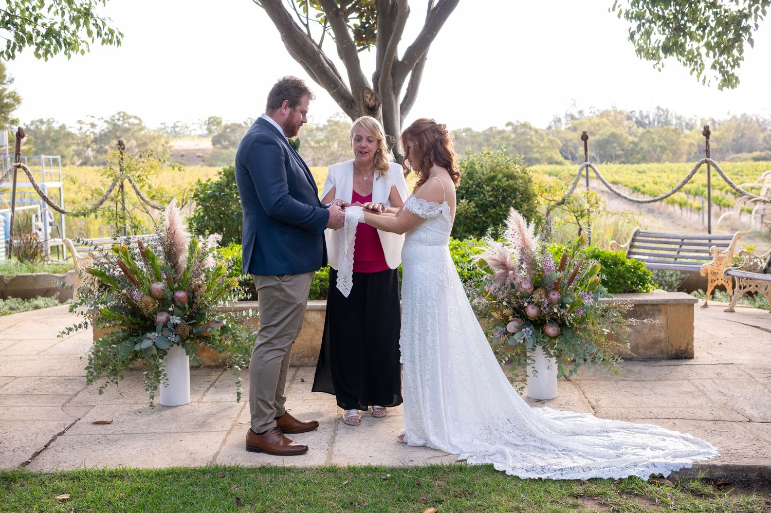 A wedding ceremony on a patio overlooking a scenic landscape with decorative floral arrangements.