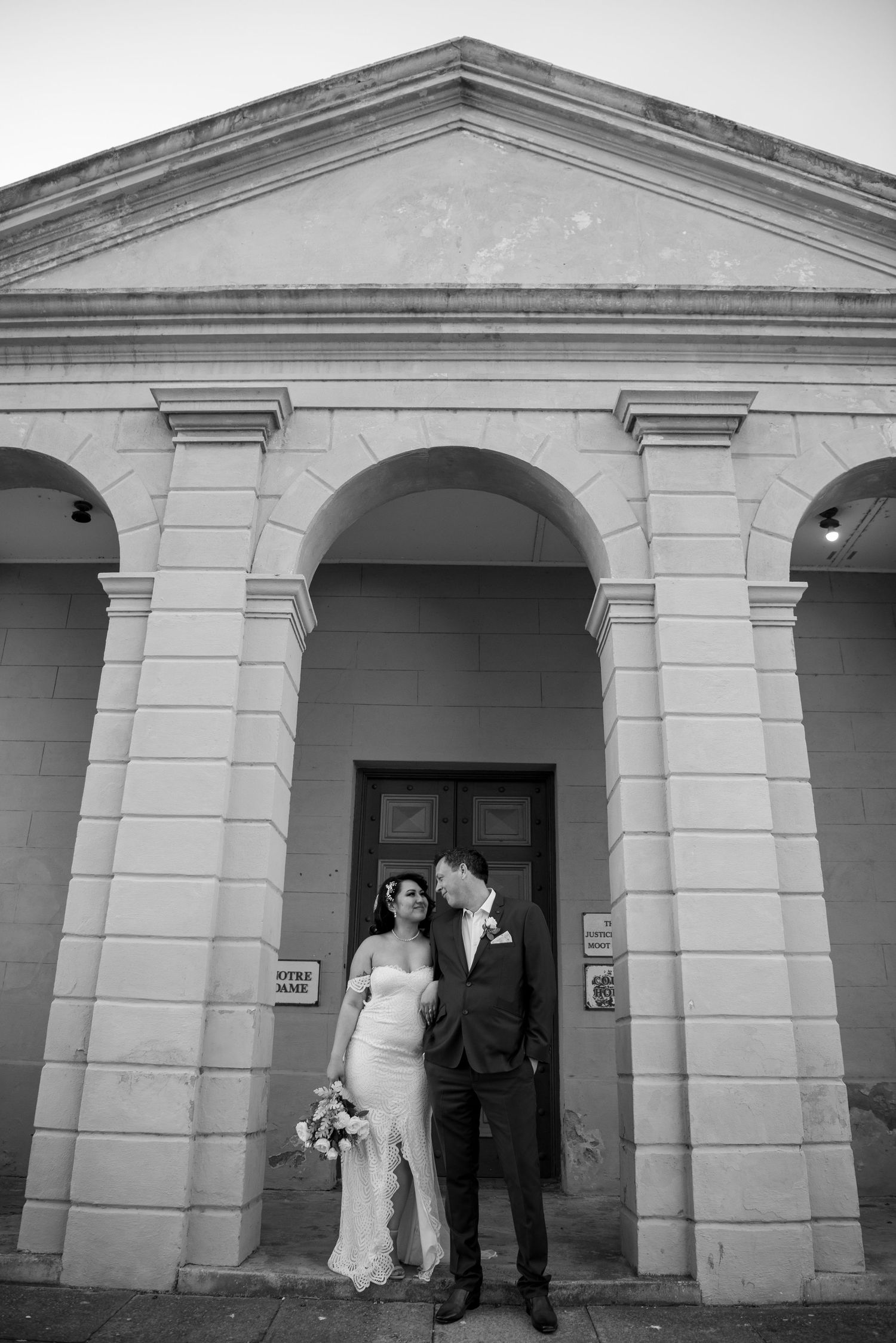 Black and white wedding portrait under classical arched colonnade.