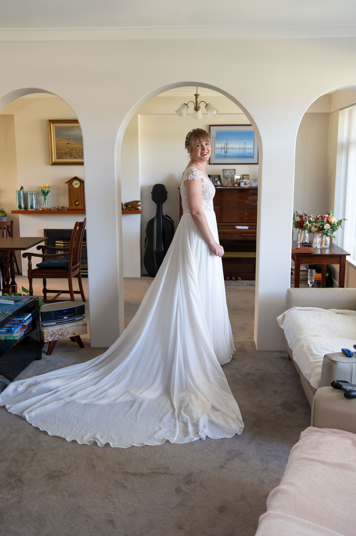 Beautiful wedding dress with a flowing train displayed in an elegant indoor setting with arched doorways.