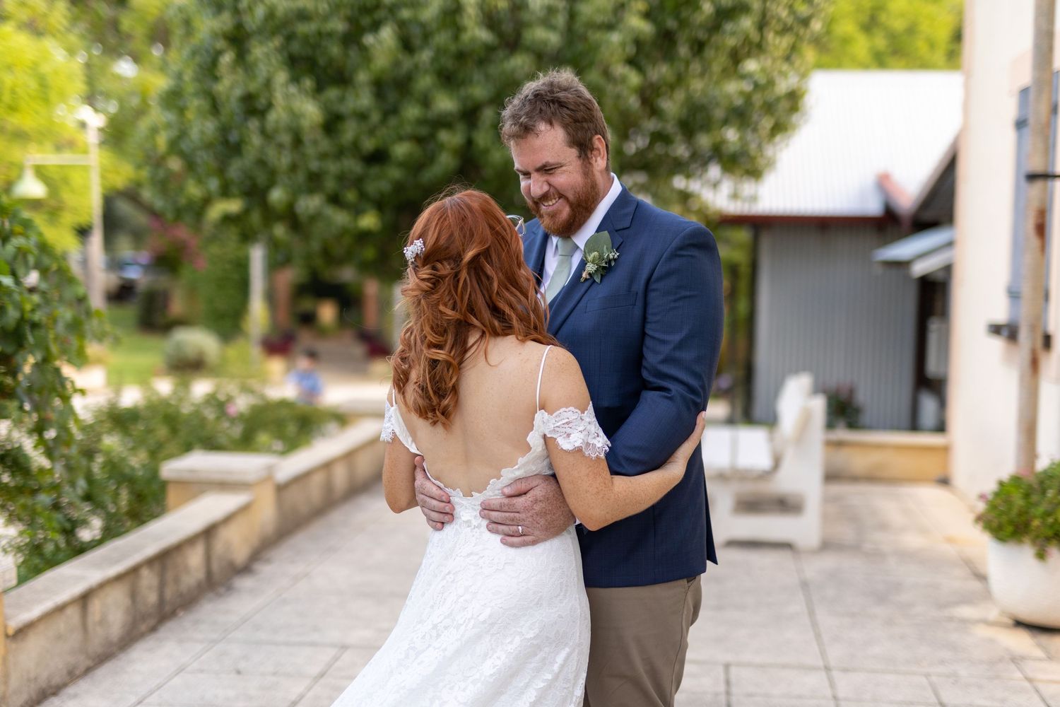 A tender moment between a couple in formal attire on a stone pathway.