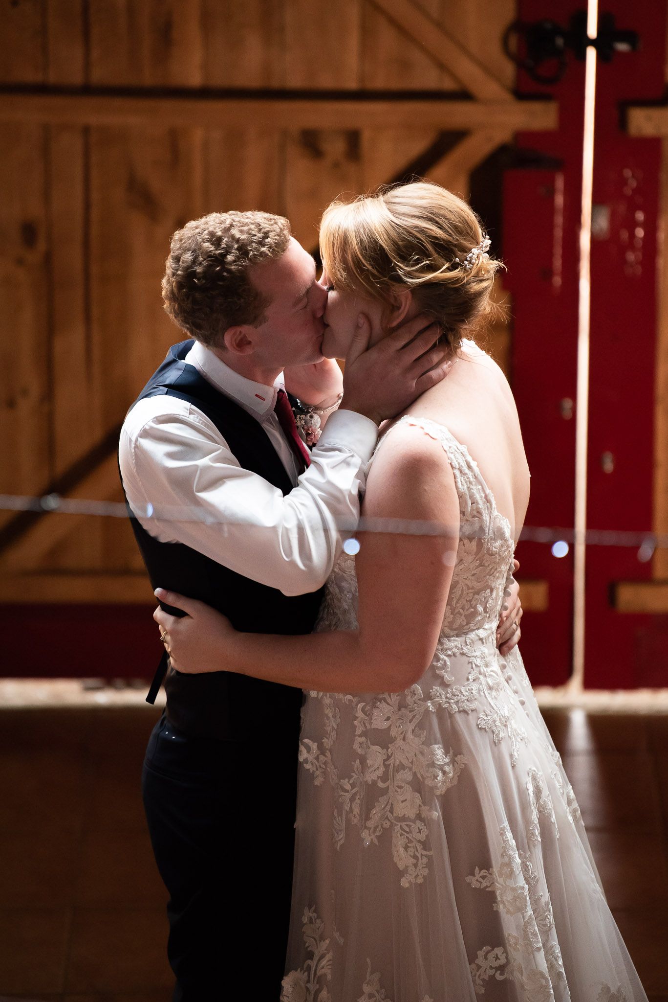 A romantic sequence of wedding photos showing a couple dancing and kissing in a rustic barn setting.