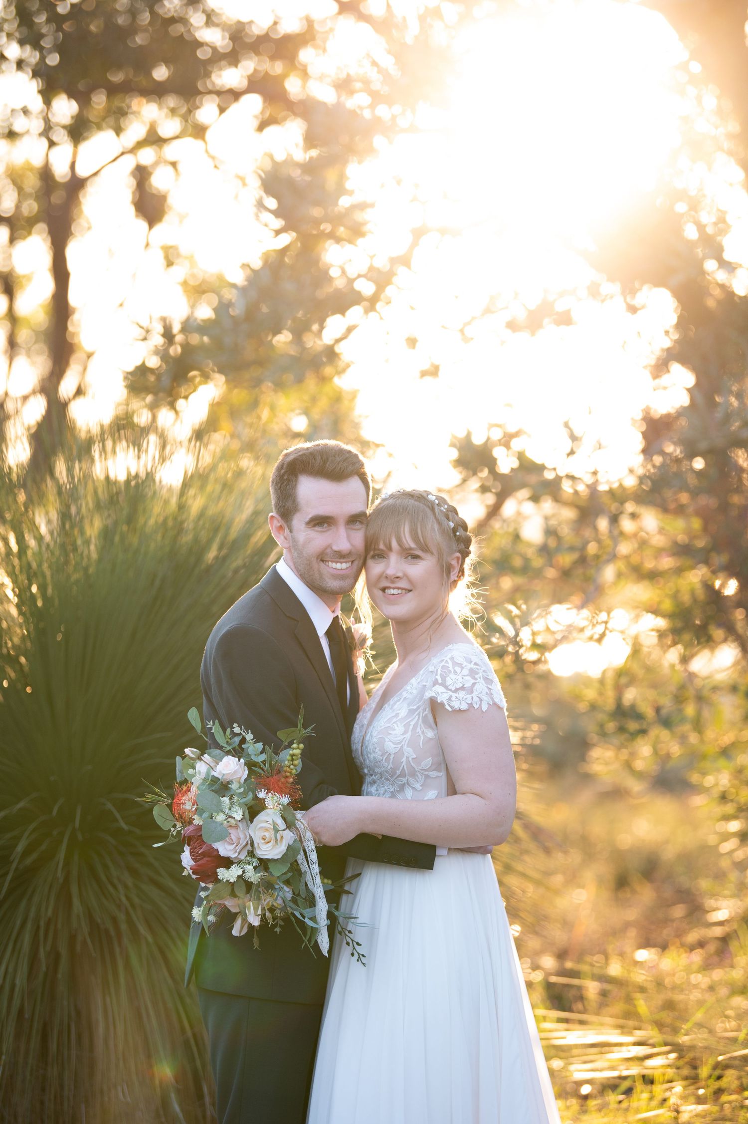 Romantic sunset portrait of couple with floral bouquet and garden backdrop.