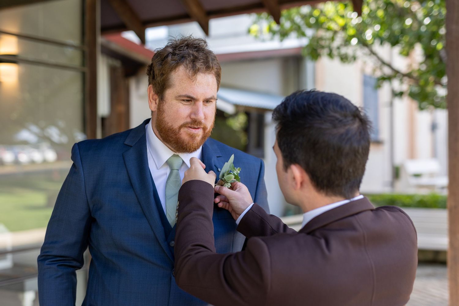 Wedding party members in navy suits sharing a celebratory moment outdoors.