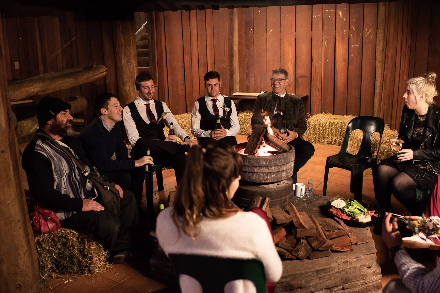 Guests seated in elegant formal attire at wooden tables in a rustic barn-like venue for a festive celebration.