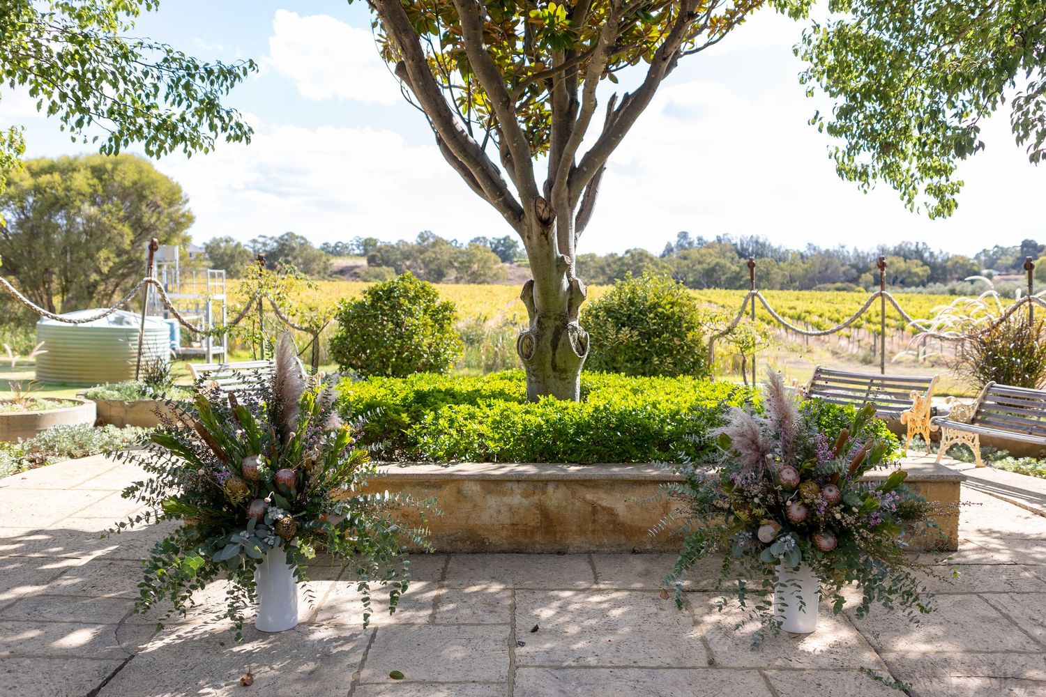 Scenic outdoor venue with trees and planters arranged along a stone patio wall.