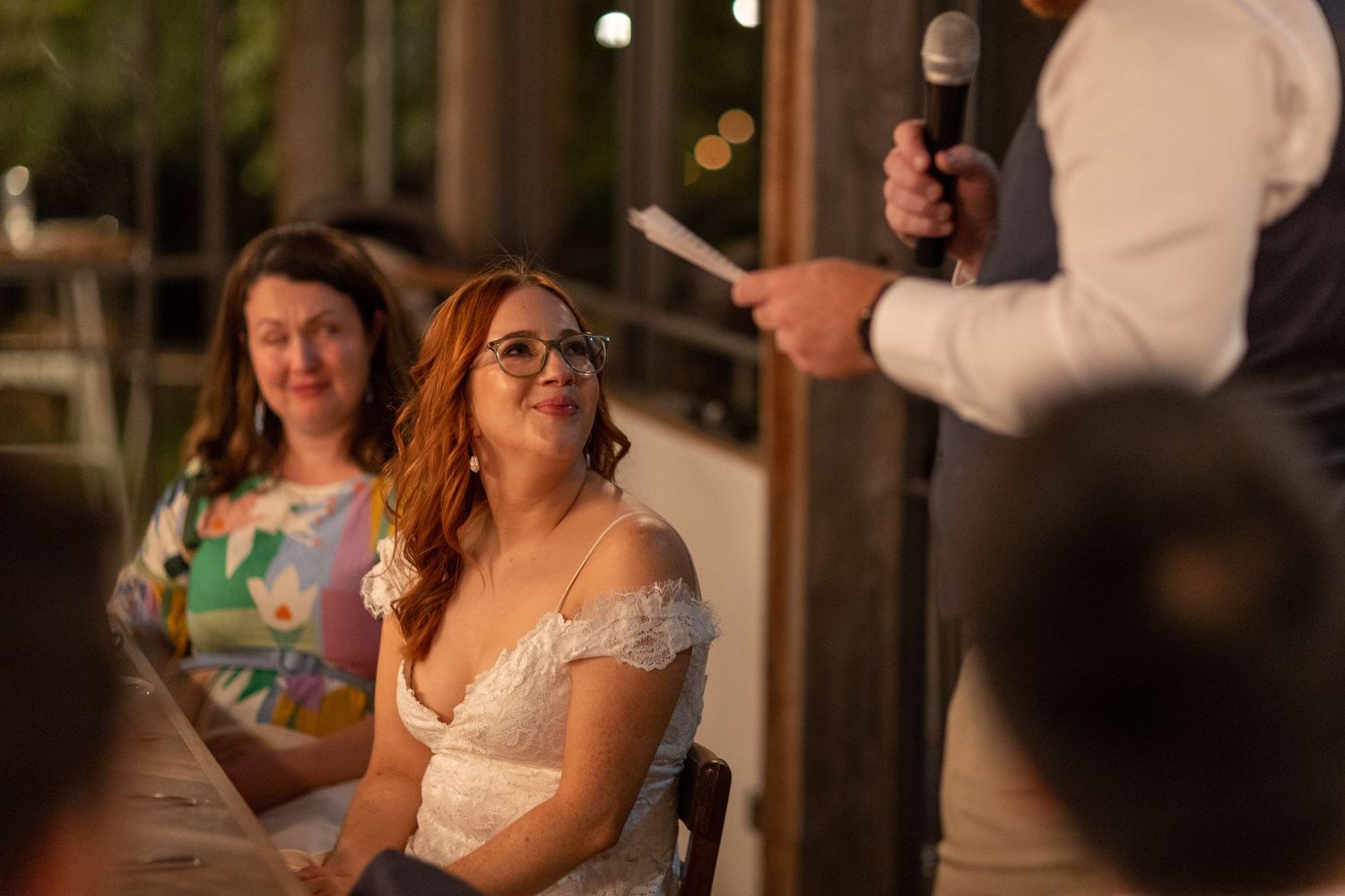 Wedding reception guests enjoying evening celebrations under warm indoor lighting.
