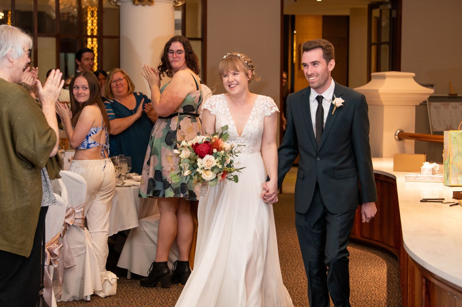 Wedding reception celebration inside an elegant venue with white decor and warm lighting.