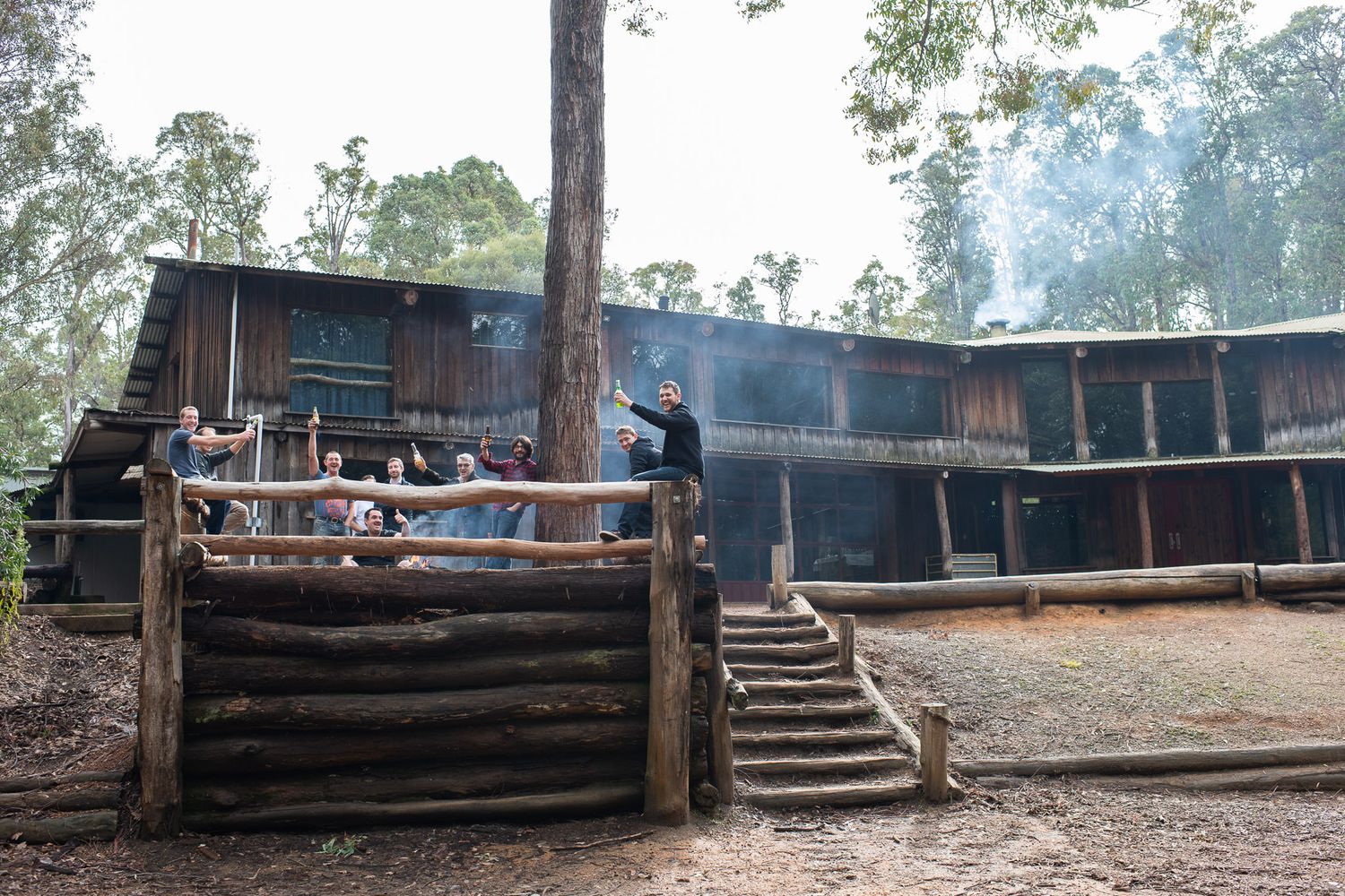 Rustic wooden buildings and decking structures along a hillside create a rural countryside atmosphere.