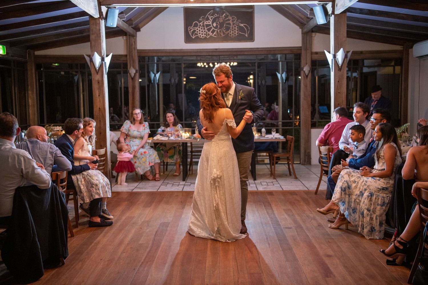 Wedding celebration in rustic indoor venue with wooden beams and white decor.