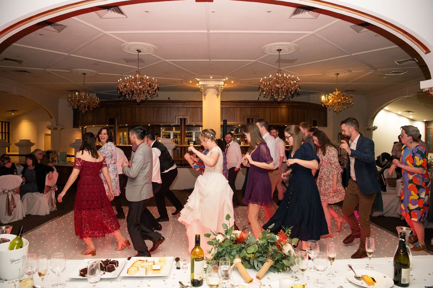 Wedding reception celebration with guests dancing and enjoying festivities in an elegant ballroom setting.