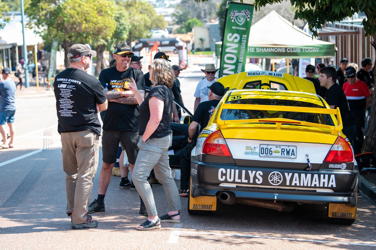 Yellow race car with Cullys Yamaha branding parked at an outdoor event with spectators gathered around.