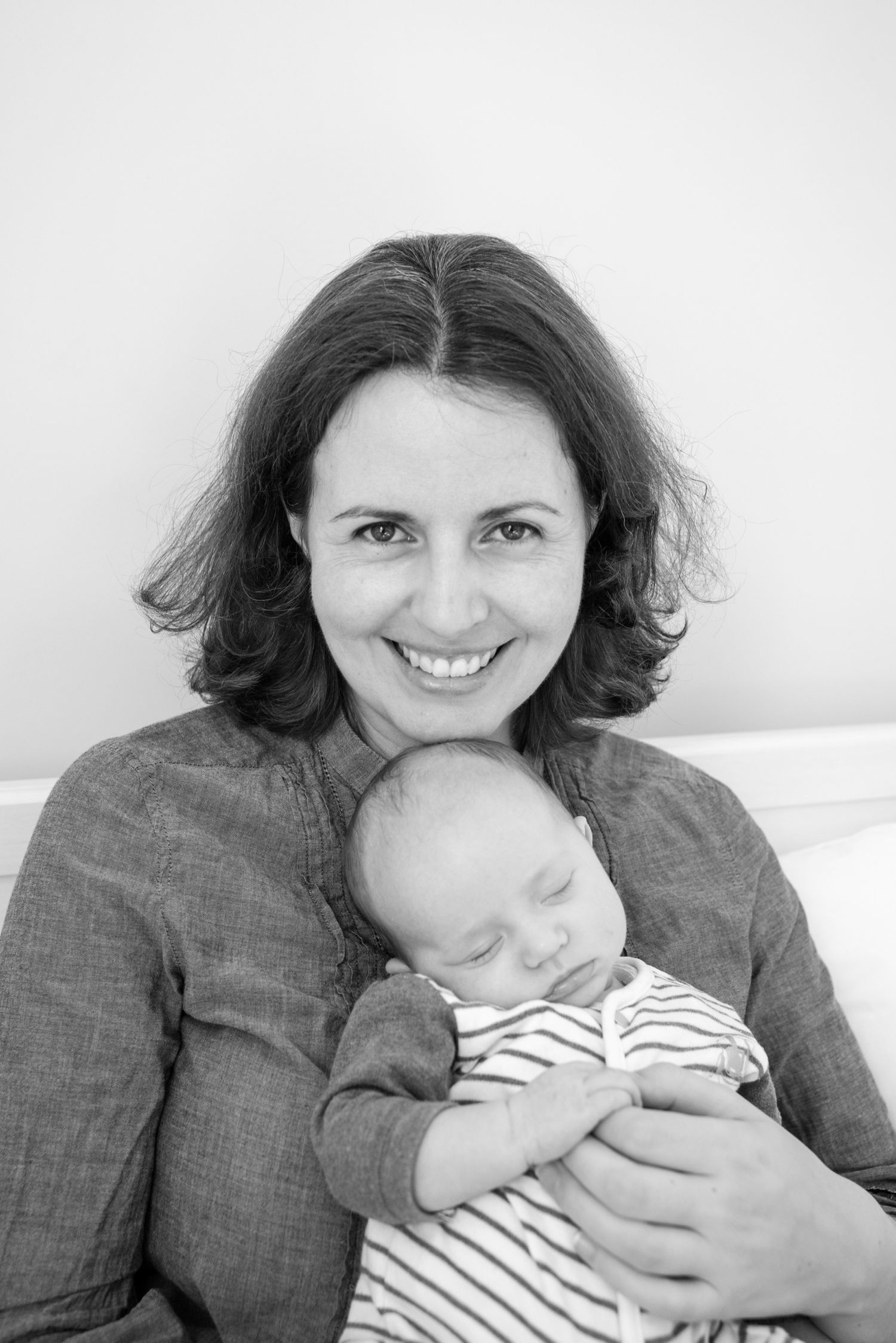 Black and white portrait of a parent tenderly holding a sleeping infant in striped clothing.