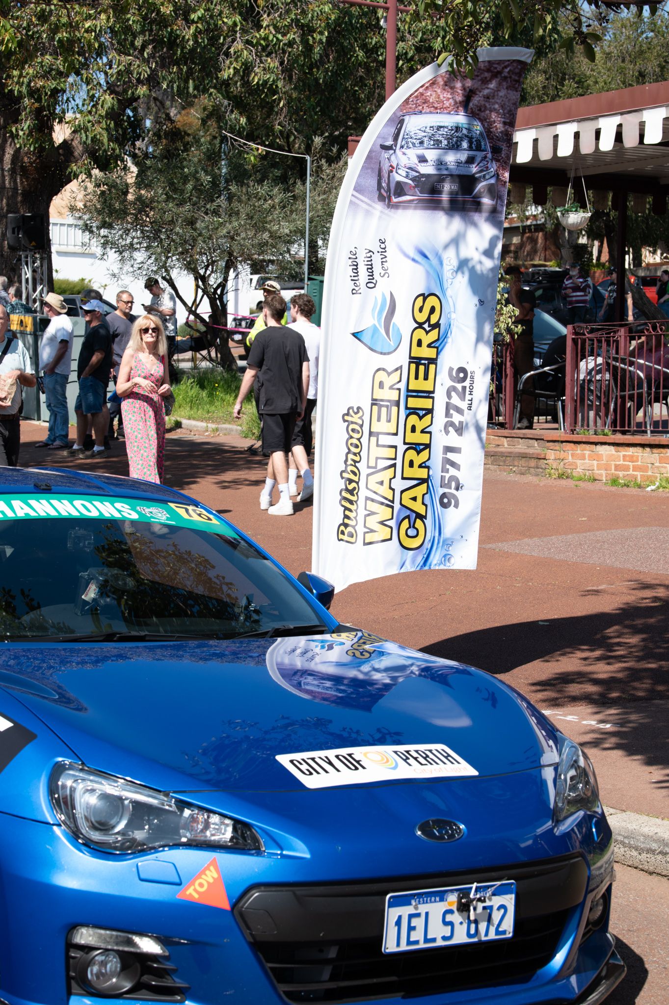 Blue Subaru BRZ sports car at a car show with a white banner displayed on the windshield.