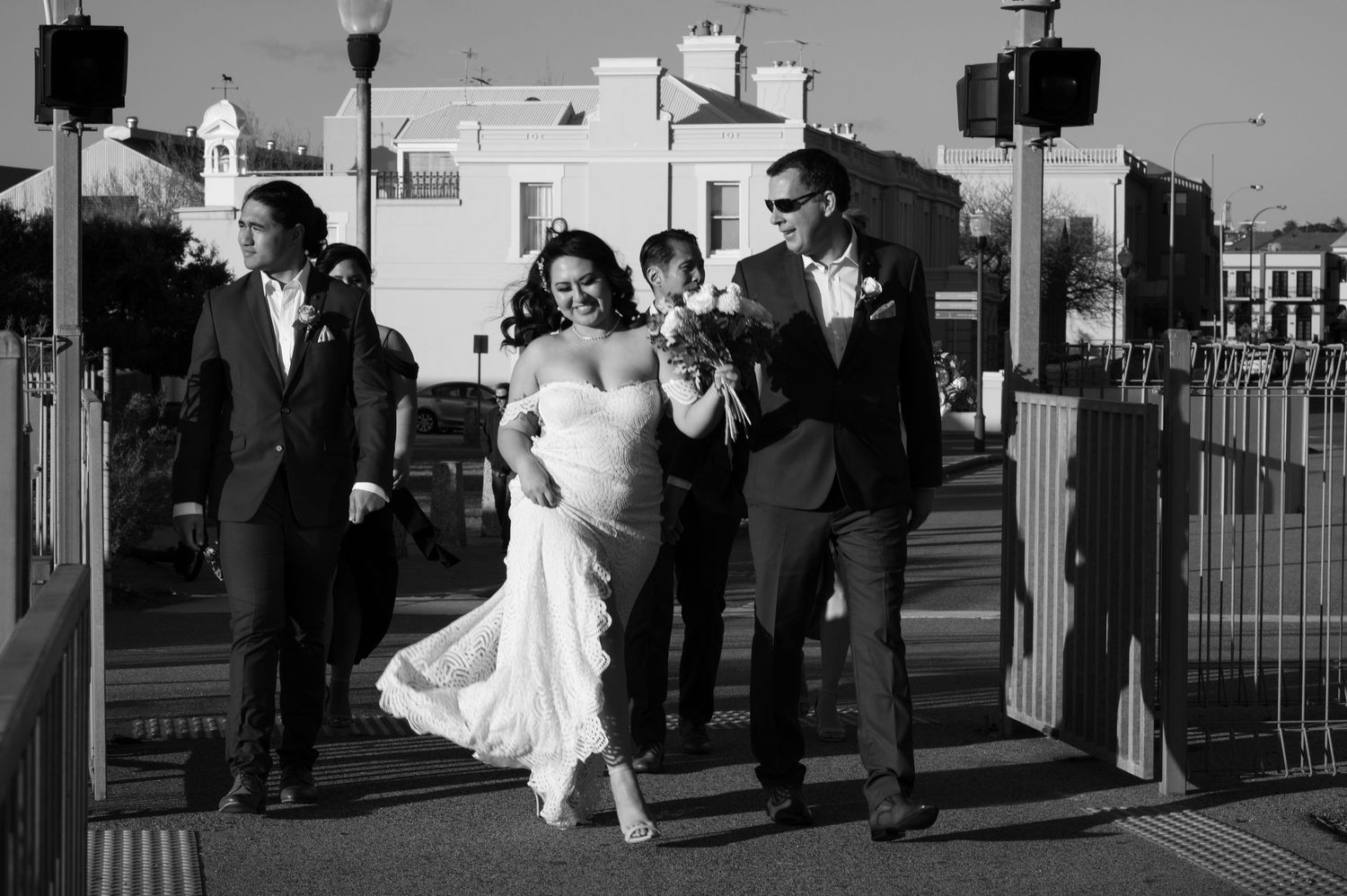 Black and white wedding photos showing silhouetted figures walking along a boardwalk or deck by the sea at sunset.