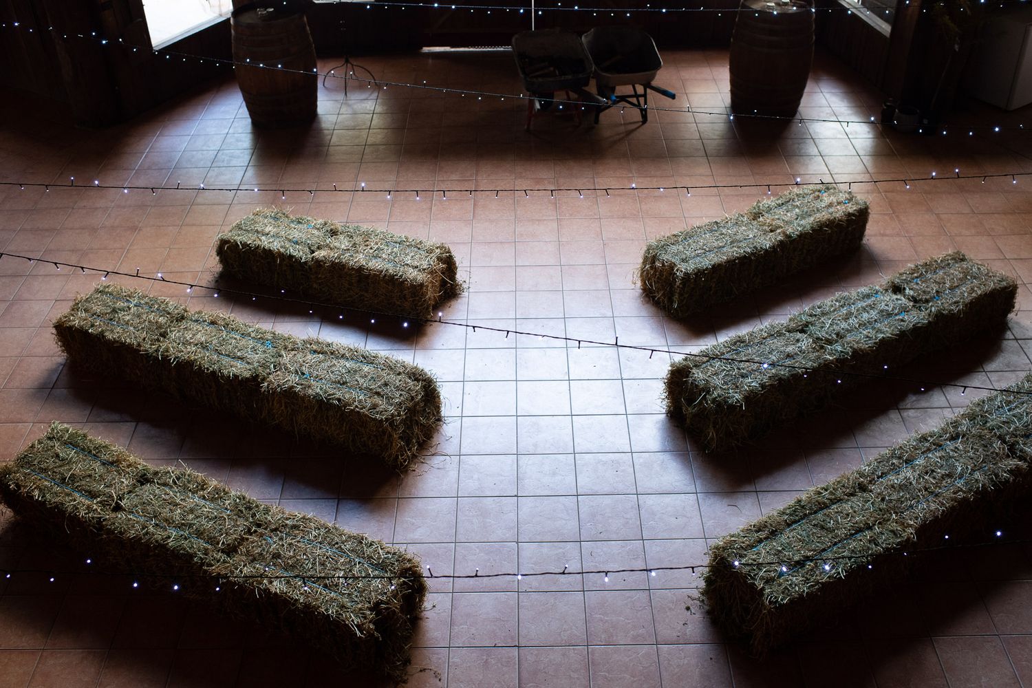Six moss-covered stone benches arranged symmetrically on brown tile flooring in a dimly lit interior space.