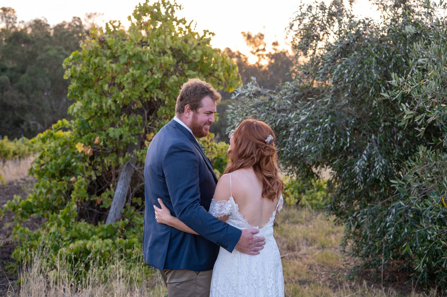 A romantic sunset wedding portrait with couple embracing outdoors.