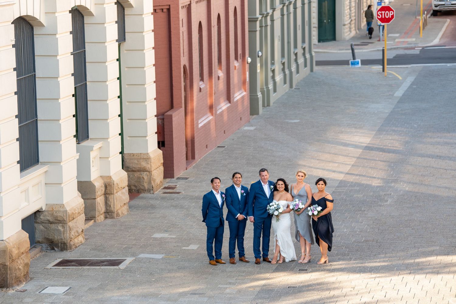 A bridal party poses together on a historic cobblestone street surrounded by classic architecture.