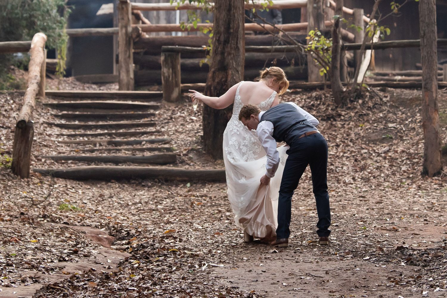 At dusk in a wooded park, a couple shares an intimate dance pose among autumn leaves and rustic wooden features.