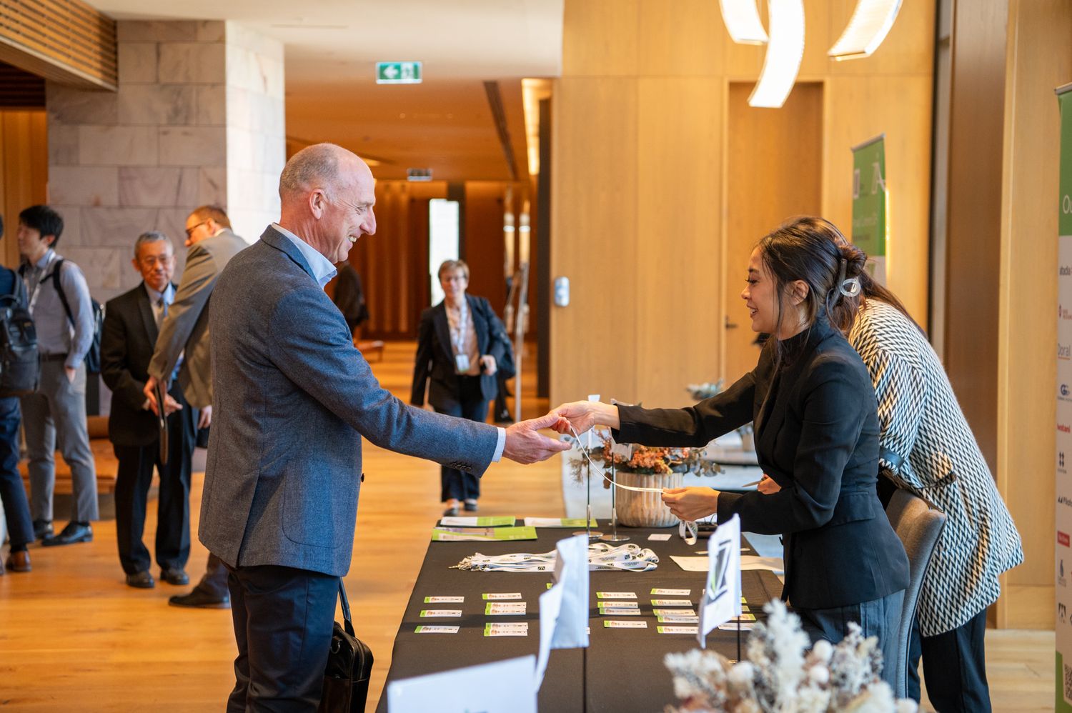Business professionals networking and shaking hands in a warmly lit conference hall.