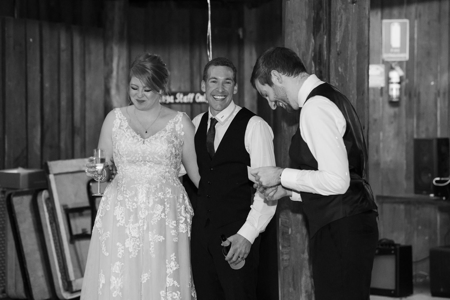 Wedding couple dancing together during their first dance in a rustic wooden venue with soft lighting.