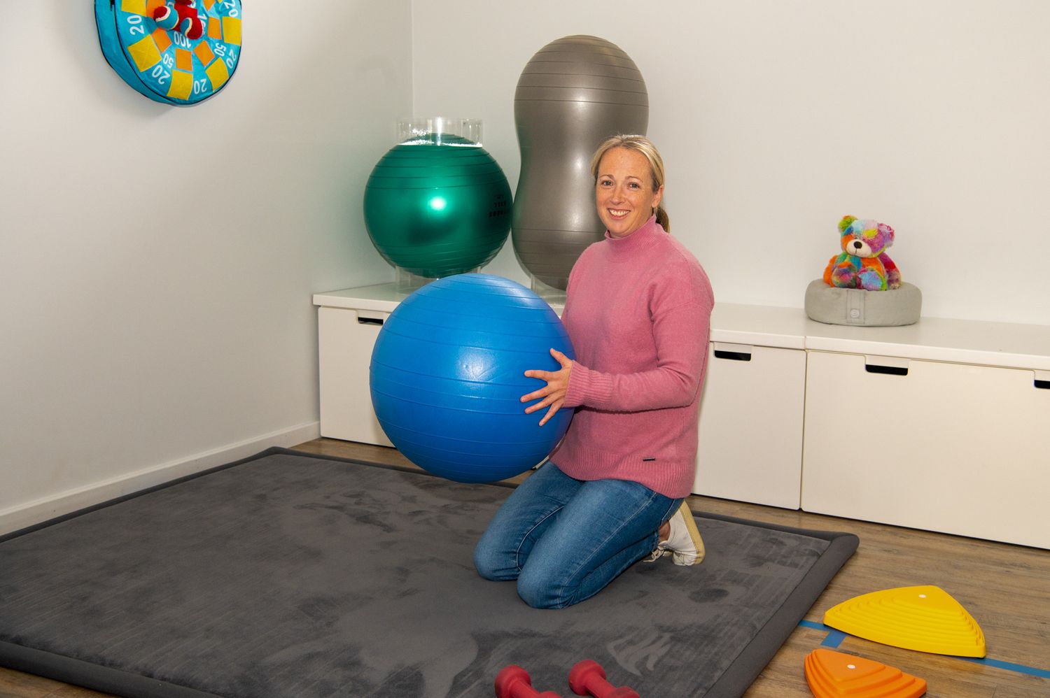 A series of frames showing an exercise ball being used in a home workout space with white storage furniture.