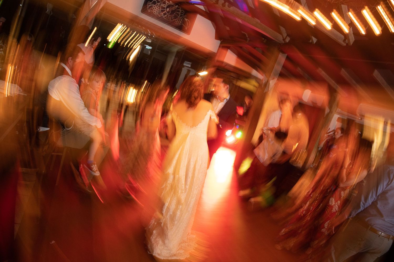 A motion-blurred photo of wedding reception dancing with red lighting effects.