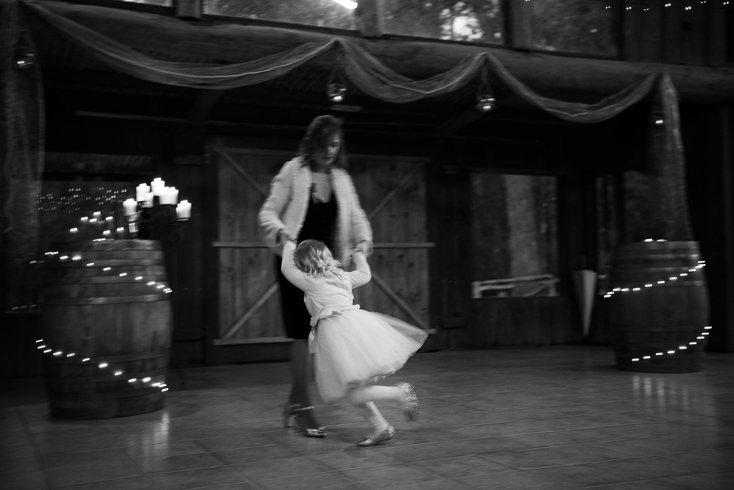 A couple dances together in an elegant ballroom decorated with draped fabric and string lights in black and white.