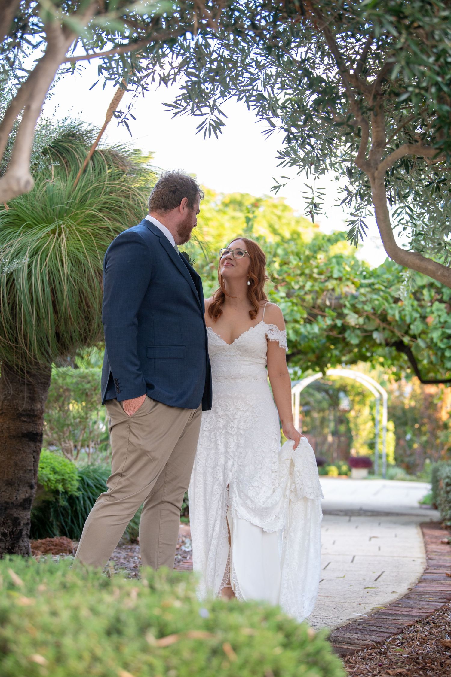 A romantic garden path moment with olive trees creating a natural outdoor wedding setting.