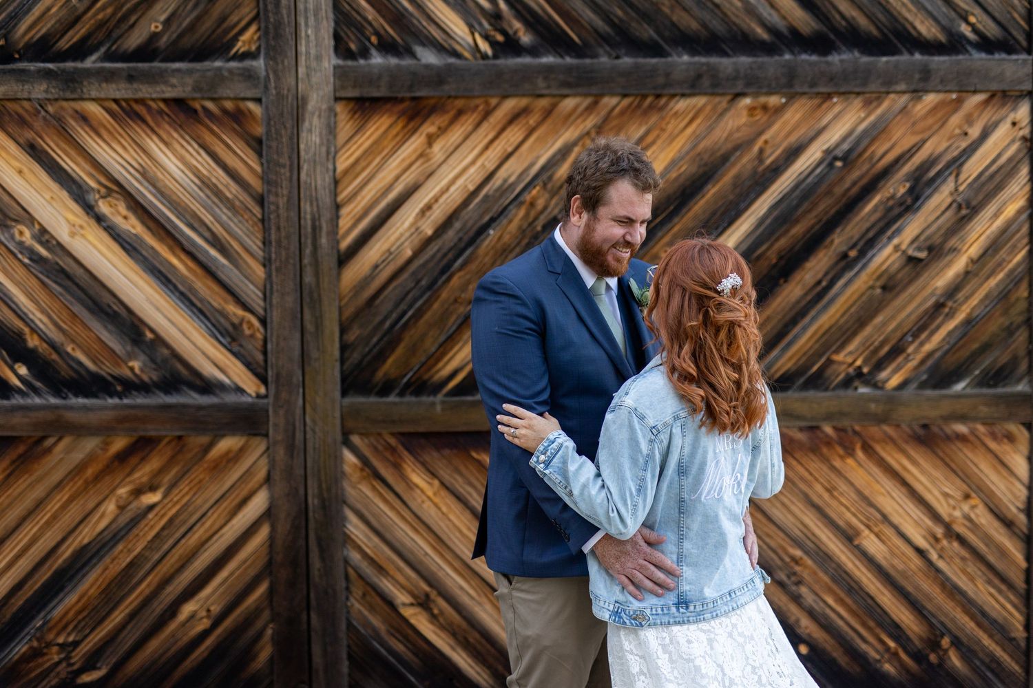 Newlyweds sharing an intimate moment against a rustic wooden wall background.