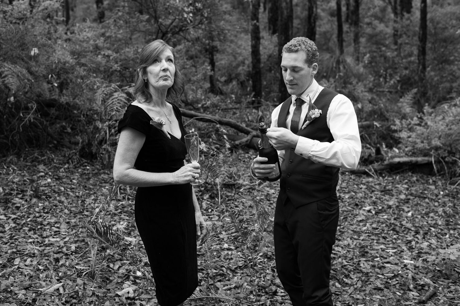A couple sharing an intimate moment while dancing together in a rustic outdoor forest setting.