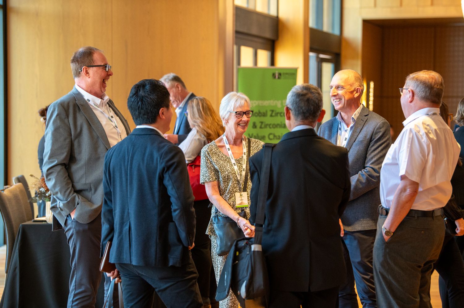 A group of people having a networking conversation in a conference hall setting.
