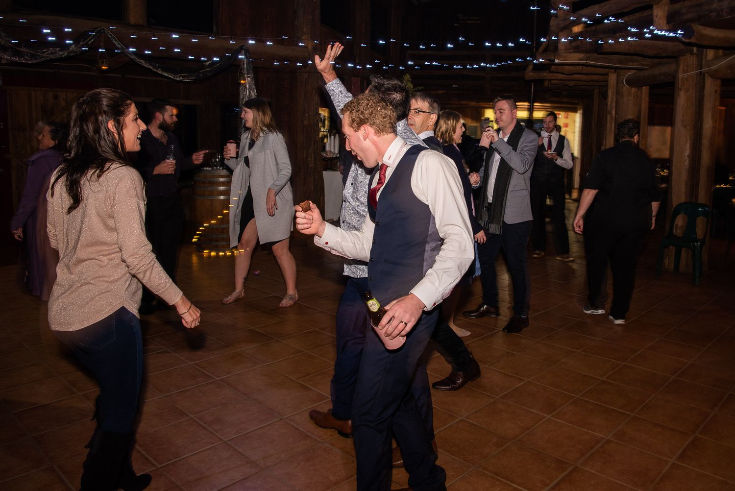 A couple dances together in a dimly lit ballroom with other dancers in the background.