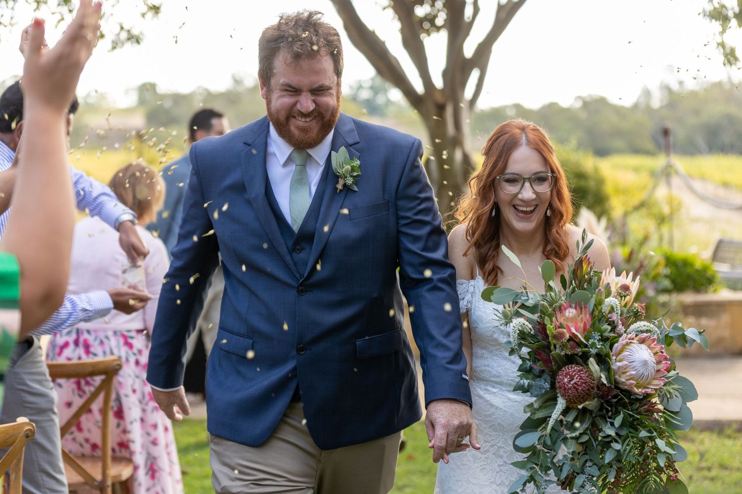 A romantic outdoor wedding celebration with newlyweds and guests celebrating during golden hour at a scenic venue.