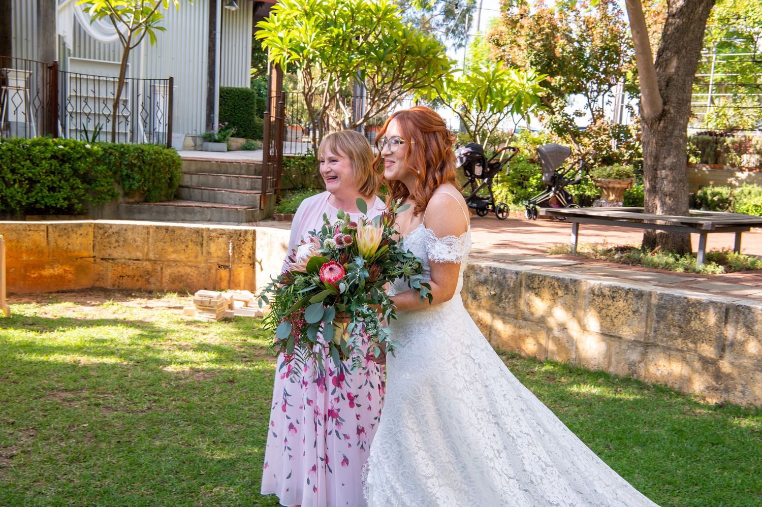 Two people sharing a joyful moment at an outdoor wedding ceremony with floral bouquets.