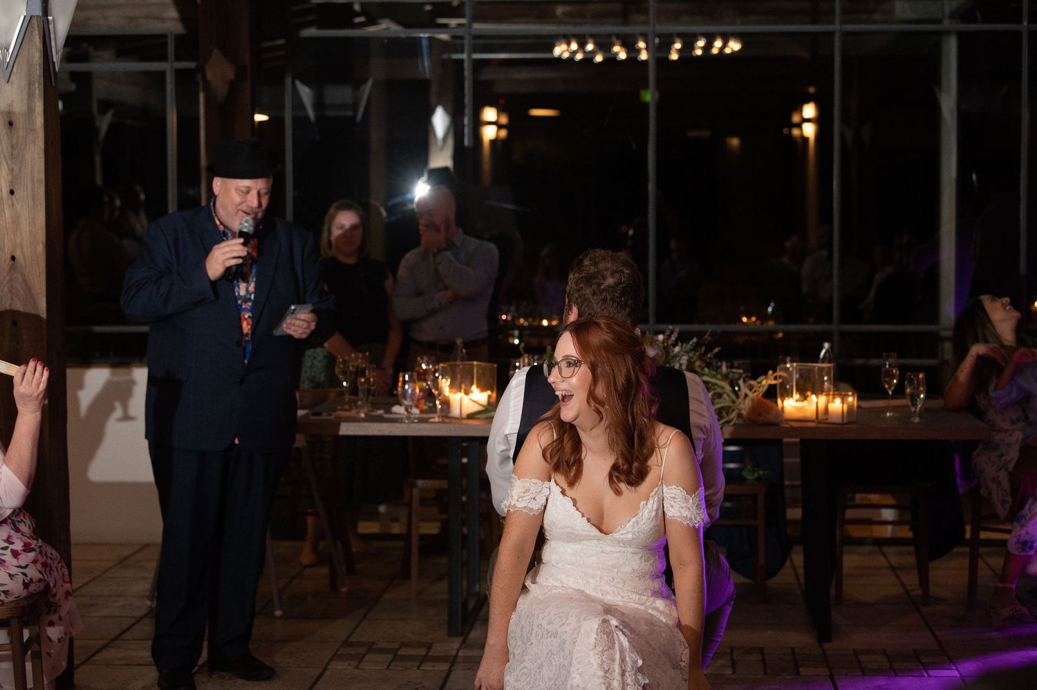A festive indoor wedding reception scene with purple lighting and elegant decor.