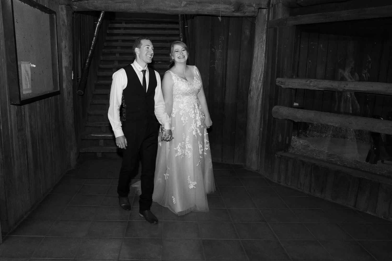 Black and white photograph of wedding couples dancing in a rustic barn venue.