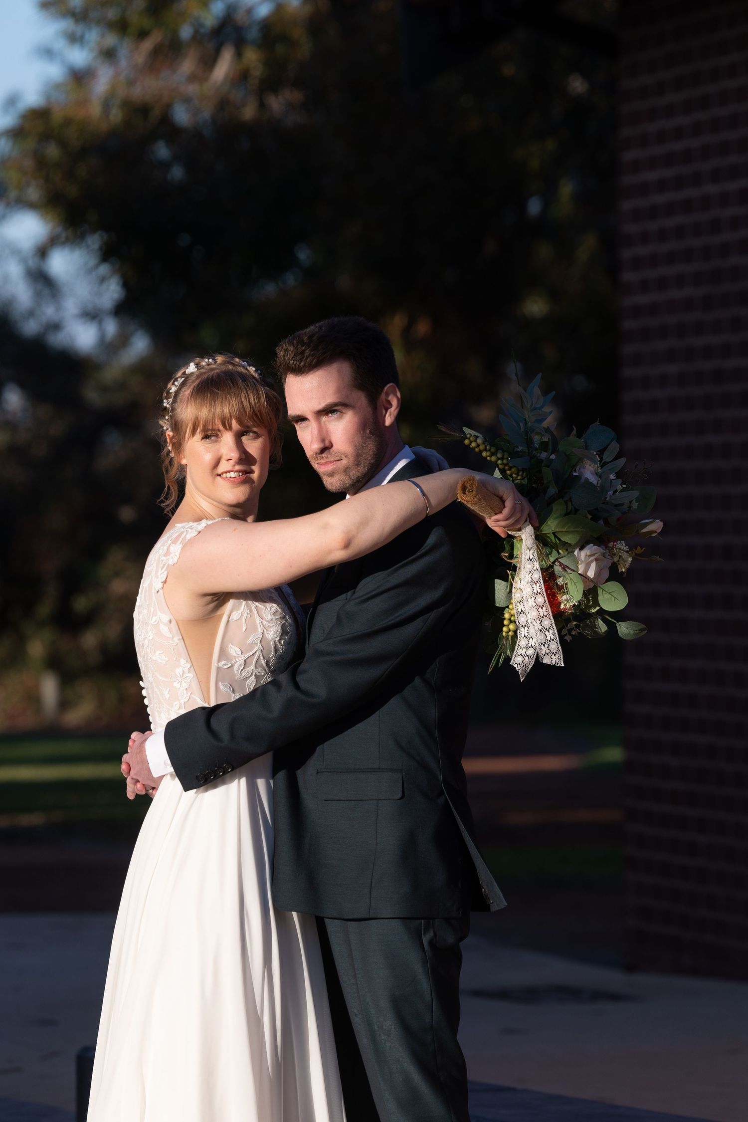 Wedding couple embraces in an intimate candid moment on an outdoor terrace at sunset.