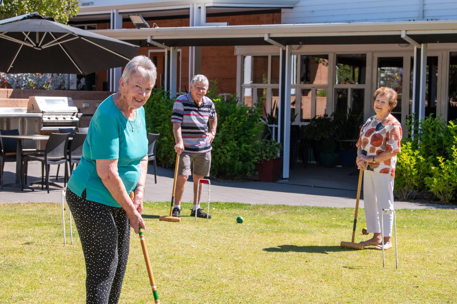 People enjoying outdoor activities on a sunny lawn at a community gathering.