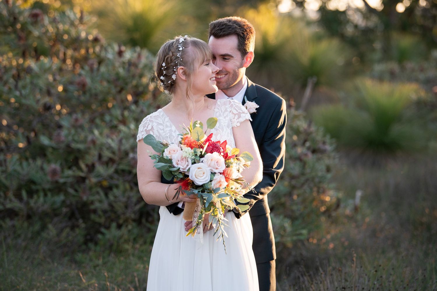 Intimate wedding portrait with couple sharing tender moment among autumn foliage.