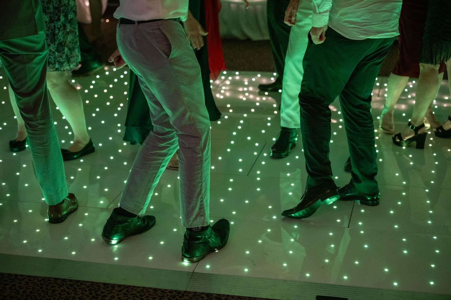 Wedding reception dance floor illuminated with twinkling lights beneath dancers' feet.
