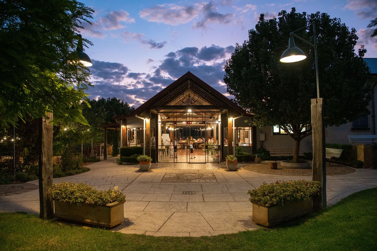 An elegant wedding venue pavilion illuminated at dusk with string lights.