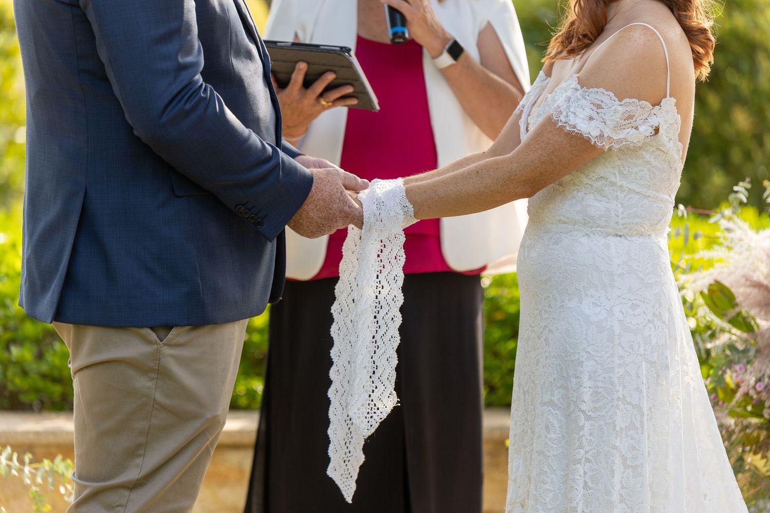 A couple participates in a traditional handfasting ceremony during their outdoor wedding.