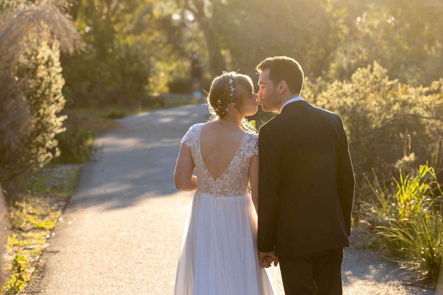 Romantic sunset portrait of newlyweds on a garden path.